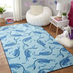 a living room with a blue rug on the floor and a white chair in front of it