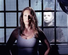 a woman standing in front of a window with a creepy face on the wall behind her