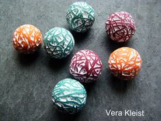 six different colored balls with white and orange designs on them sitting on a black surface