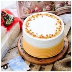 a white and yellow cake sitting on top of a wooden table next to some twine sprinkles