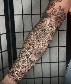 a woman's arm with flowers on it and an intricate design in the middle