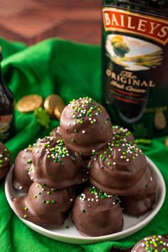 chocolate truffles with sprinkles on a plate next to a bottle of bailey's