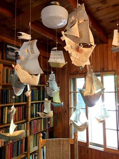 a room filled with lots of books and hanging items in the air next to a window