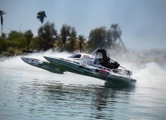 a speed boat speeds through the water with trees in the background