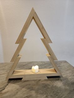 a candle is placed in the shape of a triangle on a wooden stand with two sides