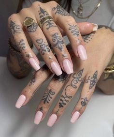 a woman's hand with tattoos on it and pink manicures in front of her