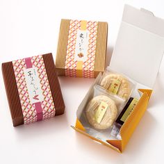 three boxes with different types of pastries in them on a white surface, one opened and the other closed