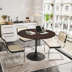 a kitchen table with chairs around it in front of a window and a laptop on top of the table