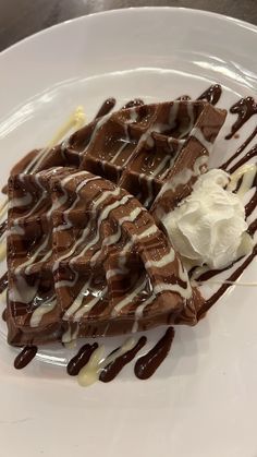 a white plate topped with waffles covered in chocolate sauce and icecream