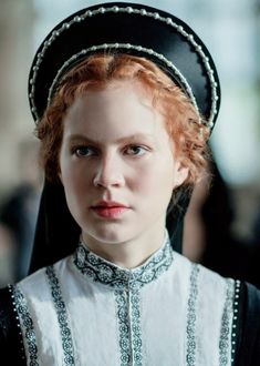 a woman with red hair wearing a black and white outfit is looking at the camera