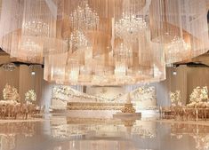 a large chandelier hanging from the ceiling in a room filled with tables and chairs