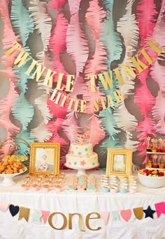 a table topped with cake and desserts next to balloon garlanded wall behind it