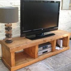 a flat screen tv sitting on top of a wooden entertainment center next to a lamp