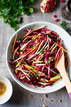 a white bowl filled with shredded carrots and radishes next to a wooden spoon