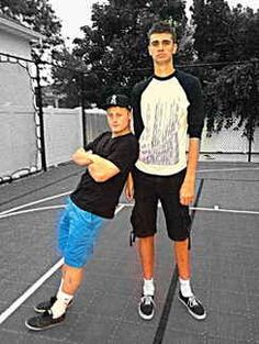 two young men standing on a tennis court posing for a photo with their arms around each other