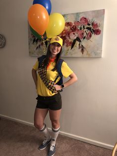 a woman in yellow shirt and black shorts holding balloons