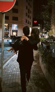 a man carrying a woman on his back while walking down the street at night time