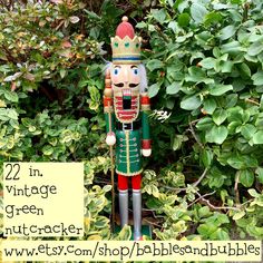 a wooden nutcracker statue in front of some bushes and trees with the words, 22 in vintage green nutcracker