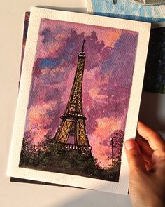 a person holding up a card with the eiffel tower painted on it