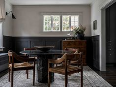 a dining room table with chairs and a black marble top in front of two windows