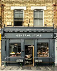 a store front with the door open on a city street in front of a brick building