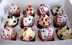 a box filled with lots of cupcakes covered in icing and playing cards