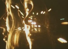 a blurry photo of a woman's face in the dark with lights behind her