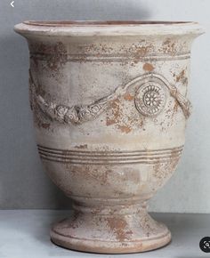 an old white vase sitting on top of a table