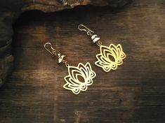 These elegant gold lotus flower earrings are perfect for adding a touch of bohemian charm to any outfit.  Crafted with two gold-colored pebble-shaped beads and a delicate lotus flower charm, they dangle gracefully from gold-plated ear wires.  Lightweight and eye-catching, these one-of-a-kind earrings are ideal for everyday wear or special occasions.  Their simple yet timeless design pairs easily with both casual and dressy looks. SIZE Total length: 5.5 cm Width: 3 cm Lotus flower charm: 2.5 x 3 Bohemian Gold Flower Earrings, Gold Brass Flower-shaped Earrings, Bohemian Gold Leaf-shaped Jewelry, Bohemian Leaf-shaped Metal Earrings, Bohemian Leaf-shaped Brass Jewelry, Boho Yoga, Gold Lotus, Yoga Jewelry, Gold Earrings Dangle