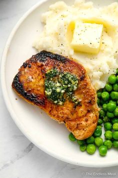 a white plate topped with meat, mashed potatoes and peas