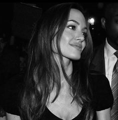 a black and white photo of a woman with long hair wearing a dress at a party