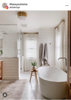 a large white bath tub sitting in a bathroom next to a wooden cabinet and mirror