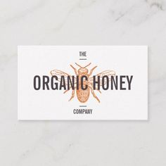 the organic honey company logo is displayed on a white marble surface with an orange and black bee