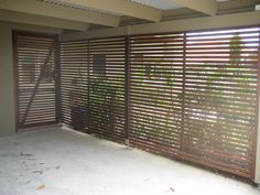 an empty room with wooden slats covering the walls and floor, in front of a sliding glass door