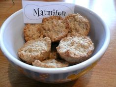 a bowl filled with muffins sitting on top of a wooden table next to a sign