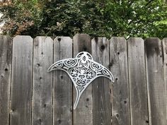 a metal bird sitting on top of a wooden fence