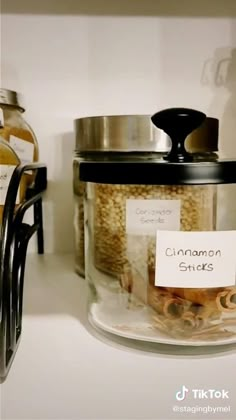 there is a jar with cinnamon sticks in it on the counter next to other jars