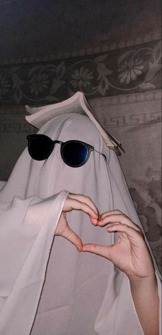 a person wearing sunglasses making a heart shape with their hands