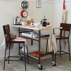 a kitchen with two stools and a small table in the middle, next to a clock