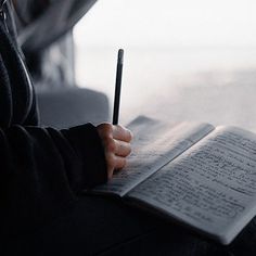 a person holding a pen and writing on a book