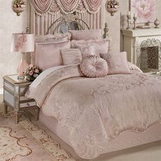 a bed with pink comforters and pillows in a bedroom