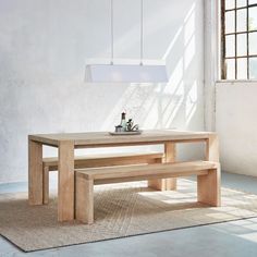 a wooden table with two benches in front of it and a light fixture hanging from the ceiling