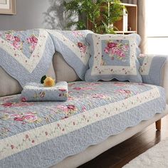 a couch covered in blue and white quilts with flowers on it's back