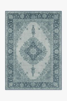 a blue rug with an ornate design on the middle and bottom, in front of a white wall