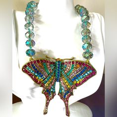 a necklace with multicolored beads and a butterfly shaped pendant on a mannequin