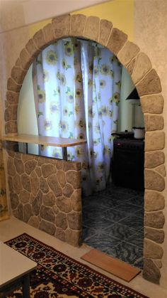 a living room with a stone arch and rug on the floor next to it,