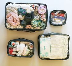 four suitcases filled with clothes and other items on a table top, all packed in different sizes