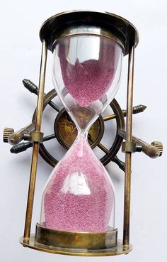 an hourglass with pink sand inside on a white background