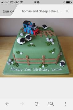 a birthday cake with a train on the top and farm animals on the side, sitting on a table