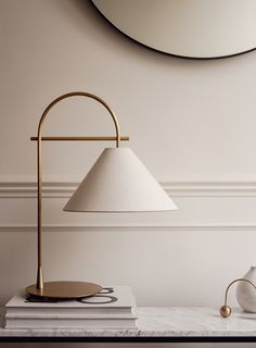 a table lamp sitting on top of a white counter next to a mirror and vase